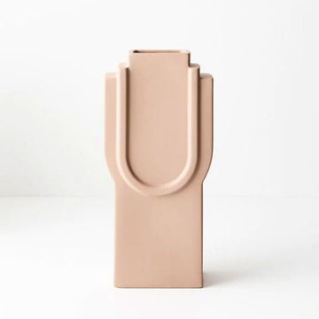 A tall vase in ceramic nude with an embossed upside down arch.