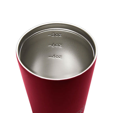 A reusable coffee cup in a dark red with a black lid and the text 'made by Fressko' on the bottom.