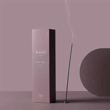 A tall rectangle box in purple with the text 'Maho' written in white. There is an incense stick burning next to the box.