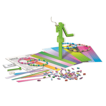 Box cover of recycled paper beads kit with a clear bottle filled with paper beads and a green crank handle on top. More coloured paper beads are next to the bottle.