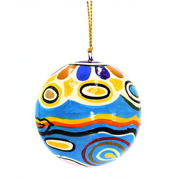 A round Christmas bauble printed with artwork by Judy Watson in blue with red, orange and yellow circles.