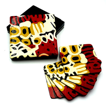 A set of six coasters are laying on top of each other next to the open box The coasters and box lid all feature artwork by Anmanari Brown in red, yellow and black.