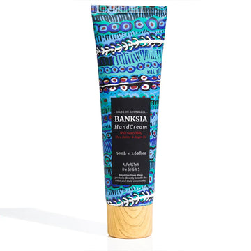 A tube of hand cream featuring artwork by Murdie Morris with a black product label and wood look lid.