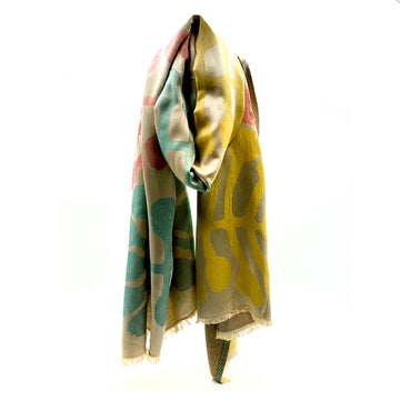 A scarf printed with artwork by Mitjili Napurrula in yellow, red and green is draped like its being worn around a neck.