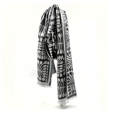 A scarf printed with artwork by Mitjili Napurrula in black and white is draped like its being worn around a neck.