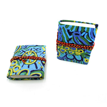 Two small notebooks pictured with red rope around them and printed with artwork by Cedric Varcoe on the covers. One notebook is lying flat and the other is standing up.