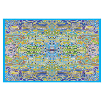 A rectangle shaped table cloth with a blue border and printed with artwork by Judy Watson. The artwork features circles and lines in yellow, blue and green.