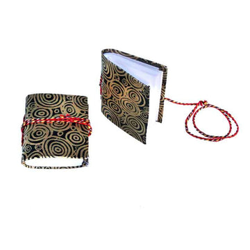 Two small notebooks pictured with red rope around them and printed with artwork by Nelly Patterson on the covers. One notebook is lying flat and the other is standing up.