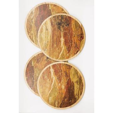 Set of four round placemats stacked in an open square box. The placemats are made from gum bark.