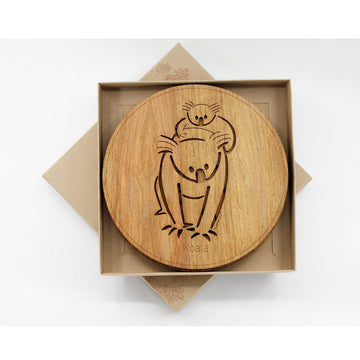A set of four round wooden placemats inside an open square box. The placemat has a cut out of a koala with a baby on its back.