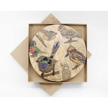 A set of four round wooden place mats printed with coloured birds in a square box.