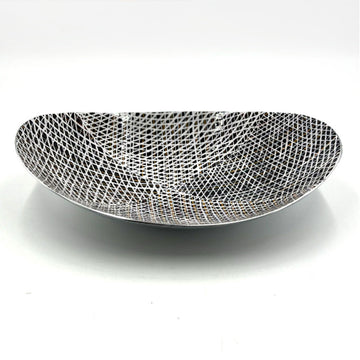 A long oval shaped stainless steel bowl printed with artwork by Paulina Puruntatameri inside in black and white.