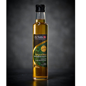 A clear jar filled with oil with a black lid and product label. The label says 'Rainforest Blend Macadamia Nut Oil'.