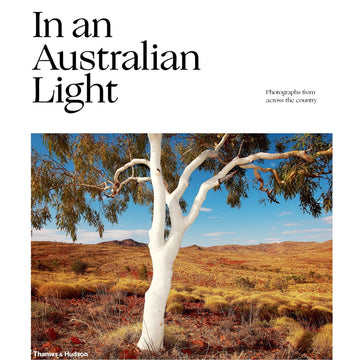 'In an Australian Light' book cover featuring a photo of a tree in the middle of a brown field with a mountain in the background.