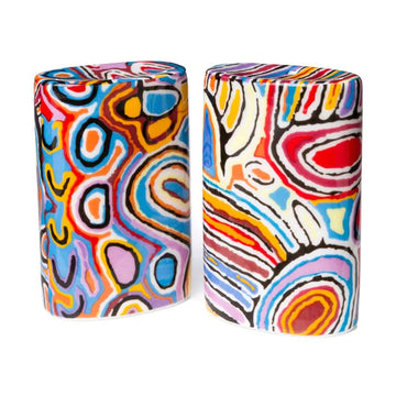 A pair of salt and pepper shakers in a tall shape with an oval top and printed with artwork by Judy Watson in red, blue and yellow.