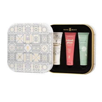 A square tin with the lid moved to the side showing three tubes of handcream inside. Each tube is a different colour with a different name.