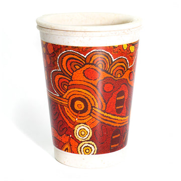 A bamboo travel mug printed with artwork by Damien and Yilpi Marks in shades of orange.