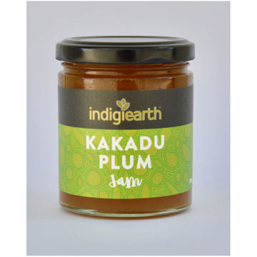 A clear jar with a black lid and a wide product label. The label says 'Indigiearth Kakadu Plum Jam' on a black and green background.
