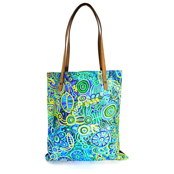 A green, yellow and blue tote bag featuring artwork by Cedric Varcoe with brown handles.
