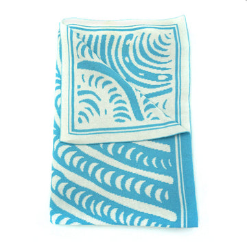 A blue and white baby blanket is folded up with one corner folded over to show the back.