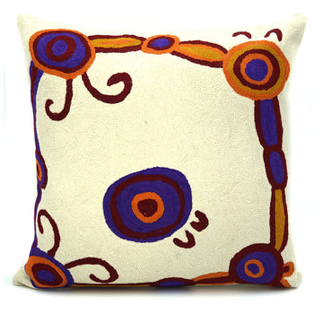 A cushion in cream with artwork by Monica Watson in orange and blue.