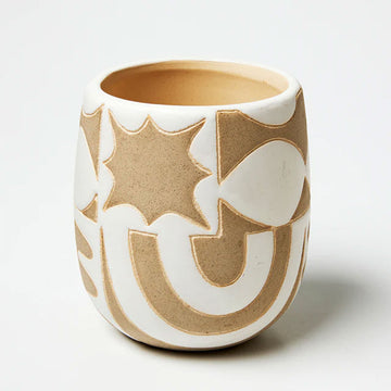 A small pot planter in natural painted in some sections in white to reveal abstract shapes.