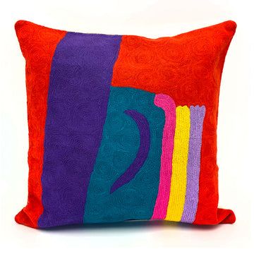 A chain stitched cushion with a red background and a wide purple vertical stripe followed by a shorter teal stripe and skinny pink, yellow and lilac stripe. The cushion is artwork by Akay Koo'olia.