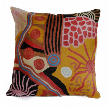 A woven cushion printed with artwork by Damien and Yilpi Marks in yellow, browns and reds.