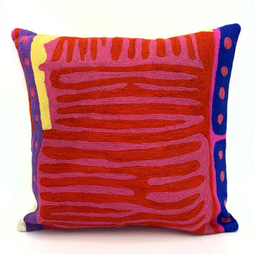 A chain stitched cushion featuring artwork by Akay Koo'olia in pink, red and blue.