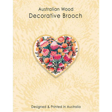A wooden brooch in the shape of a heart with flowers inside on a light brown patterned background with the heading 'Australian Wood Decorative Brooch'.