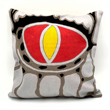 A chain stitched cushion featuring artwork by Edward Malati Yunupingu with a red and yellow eye surrounded by black and white shapes on a brown background.