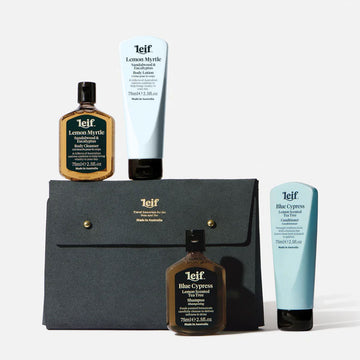 Four leif products including bottles and tubes are standing on top and next to a travel pouch in grey. The pouch has the text 'Leif' written in gold on the flap.