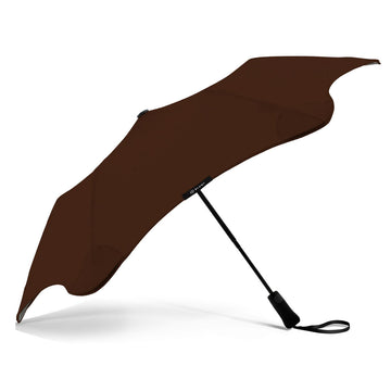 A brown umbrella is open and resting on its black handle.