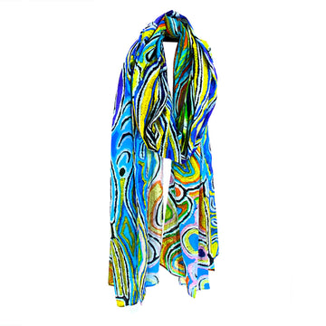 A cotton scarf printed with artwork by Judy Watson in blue and yellow, wrapped up like its being worn around a neck.