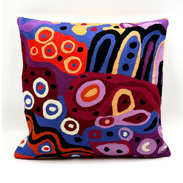 A cushion chain stitched cushion printed with artwork by Andrea Mimpitja Adamson in blue, purple, yellow and black.