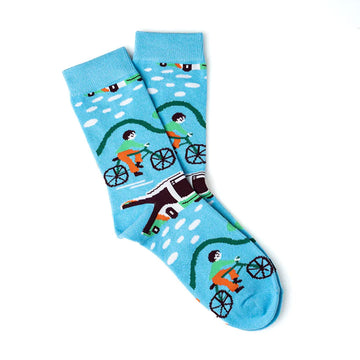 A pair of socks laying one one top of each other and printed with an image of a person riding a bike and a bus.