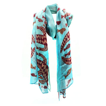 A blue cotton scarf printed with fish in artwork by Susan Wanji Wanji is wrapped up like its around a neck.