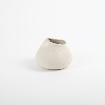 A handcrafted vase in an irregular round shape in white.
