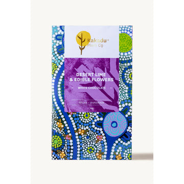 Front cover of a block of chocolate inside a box printed with Aboriginal artwork and the title 'Desert Lime & Edible Flowers White Chocolate'.