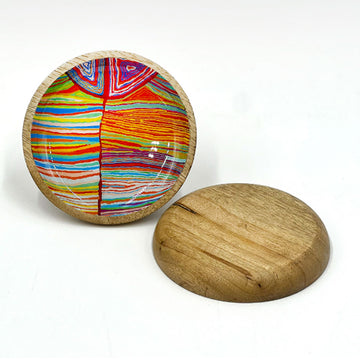 A wooden trinket dish printed with artwork by Judy Watson on the inside is standing up. Another dish is laying flat down.