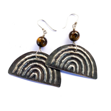 A pair of drop earrings with a tigers eye gemstone attached to a sterling silver semi circle with arches embossed in it.