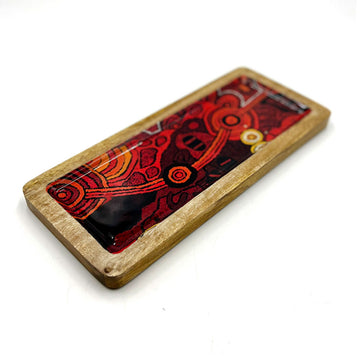A wooden rectangle tray on an angle printed with artwork by Damien and Yilpi Marks inside.