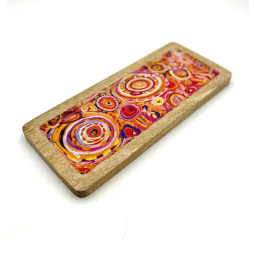 A wooden rectangle tray on an angle printed with artwork by Cedric Varcoe inside.