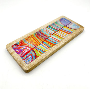 A wooden rectangle tray on an angle printed with artwork by Judy Watson inside.