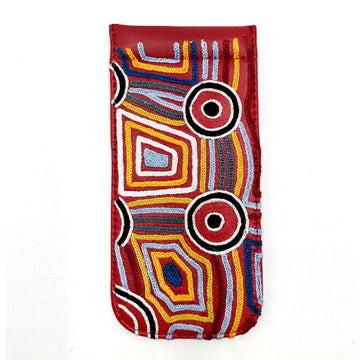 A red leather glasses case embroidered with artwork by Mary Napangardi Brown.
