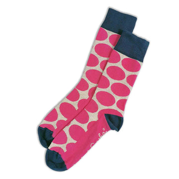 A pair of socks lying flat featuring a pink spotted print with a navy toe, heel and cuff.