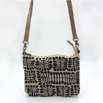 Close up of a rectangle cross body bag in tan printed with artwork by Mitjili Napurrula.