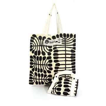 A black and white tote bag featuring artwork by Mitjili Napurrula. There is a folded up tote bag in front.