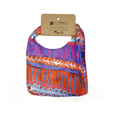 A cotton baby bib printed with artwork by Murdie Nampijinpa Morris and a brown product tag at the top.