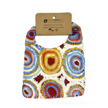 A cotton baby bib printed with artwork by Rama Sampson and a brown product tag at the top.